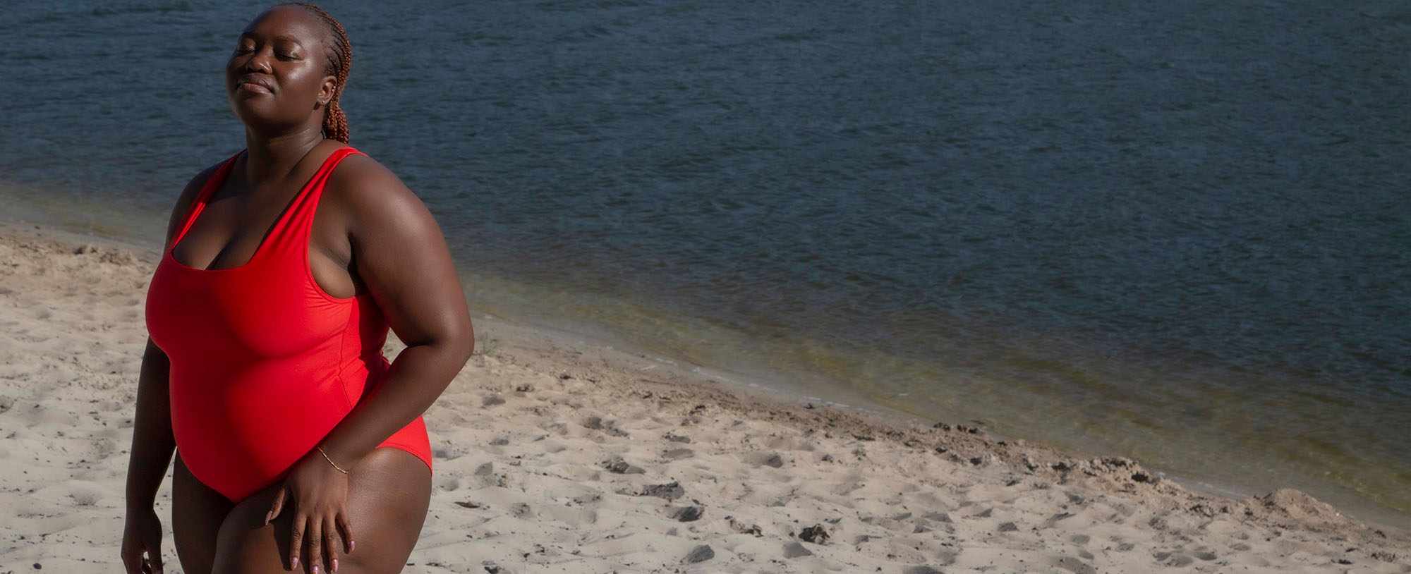 plus size model wearing a red one piece swimsuit on the beach