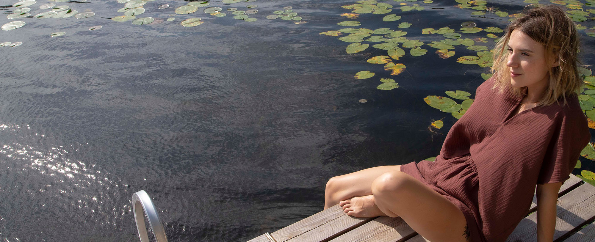 woman lounging on dock in raisin gauze v-neck top and shorts