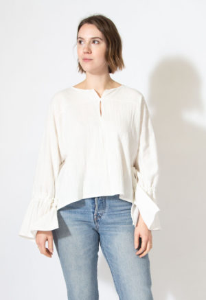 Front view of straight size model wearing white long sleeve with bell sleeves.