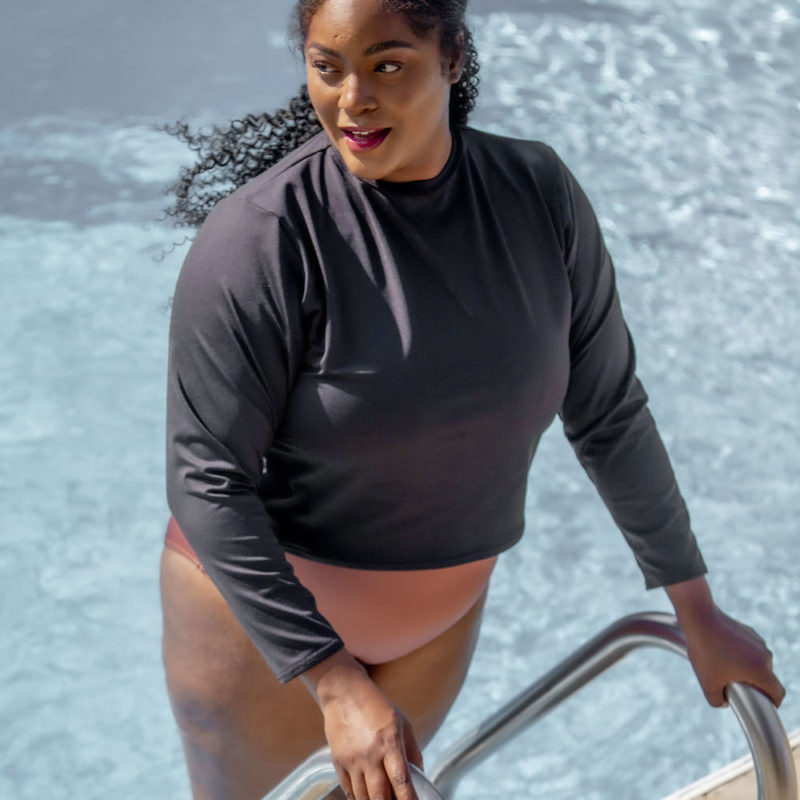 Front view of plus size model wearing Cropped Rash Guard in Black.