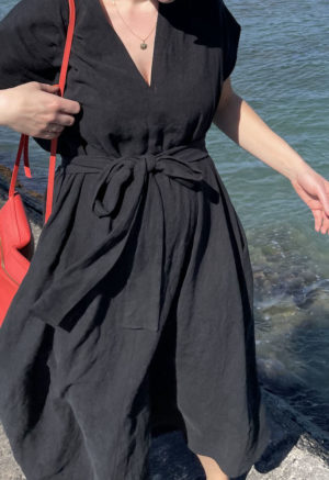 Close up front view of straight size model wearing Double V Swing Dress in Black Linen.