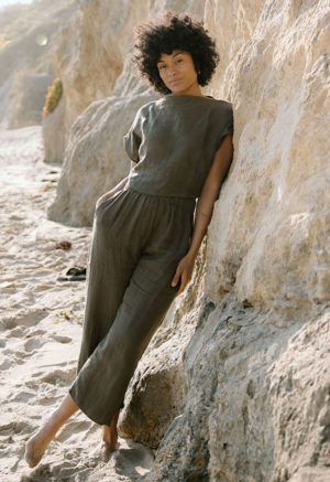woman on beach in dark green linen boatneck short sleeve top and matching wide-leg pants