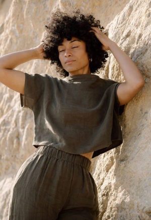 woman on beach in dark green linen boatneck short sleeve top and matching wide-leg pants