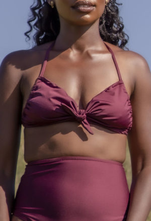 Close-up front view of straight size model in the Fig Halter Tie Top, standing in the tall grass.