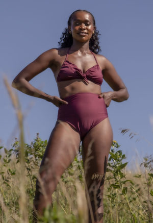 Front view of straight size model in the Fig Halter Tie Top, standing in the tall grass.