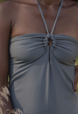 Close-up front view of straight size model in Eucalyptus Keyhole Tie One Piece standing outside by trees.
