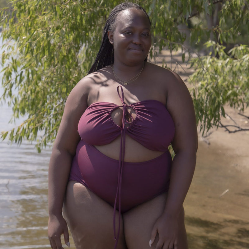 Front/side view of plus size model in Fig Retro Fit Bottoms standing in lake.