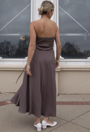 Back view of a straight size model in the Mauve Rib Everything Tank Dress, standing, standing outside in front of large windows.