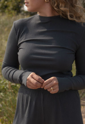Front view of a straight size model in the Blue Spruce Rib Cropped Long Sleeve Top, standing outside on grassy sand.