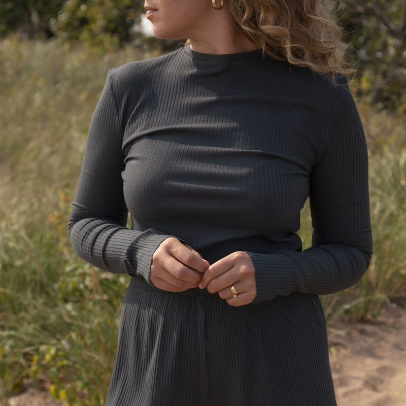 Front view of a straight size model in the Blue Spruce Rib Cropped Long Sleeve Top, standing outside on grassy sand.