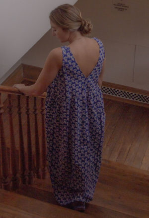 Back view of straight size model in Dark Blue Floral Reversible Tie Tank Dress standing on staircase.