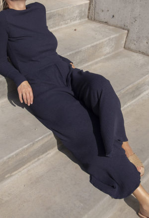 Front view of a straight size model in the Navy Rib Cropped Long Sleeve Top, sitting outside on concrete steps.
