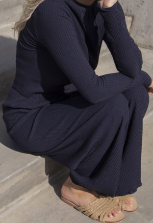 Side view of a straight size model in the Navy Rib Cropped Long Sleeve Top, sitting outside on concrete steps.