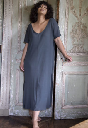 Front view of a straight size model in the Blue Spruce Rib Reversible Side Slit Dress, standing in front of ornate wooden doors.
