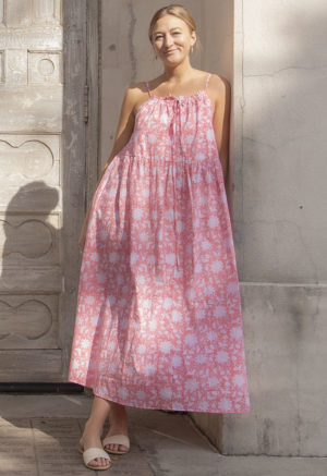 Front view of straight size model in Pink & White Floral Reversible Tie Dress standing outside in front of ornate door.