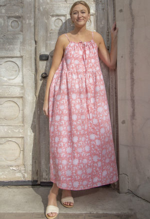 Front view of straight size model in Pink & White Floral Reversible Tie Dress standing outside in front of ornate door.