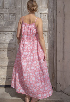 Back view of straight size model in Pink & White Floral Reversible Tie Dress standing outside in front of ornate door.