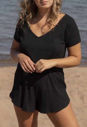 Front view of straight size model in Black Rib Reversible Short Sleeve Top standing on beach with lake in the background.