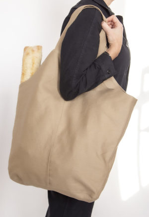 Side view of straight size model carrying Nomad Baguette Tote with baguette.
