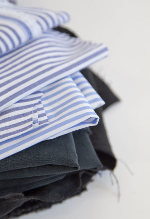 Close up view of quilt scraps including Blue & White Stripe, Light Blue & White Stripe, Liquorice, Avocado and Black.