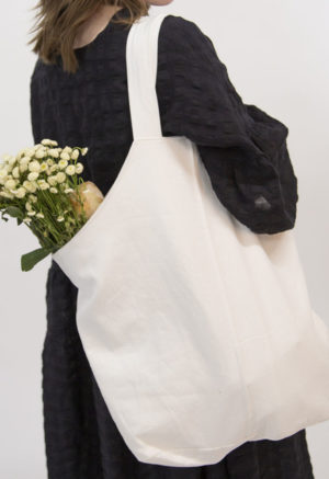 Side view of straight size model carrying White Baguette Tote with flowers.