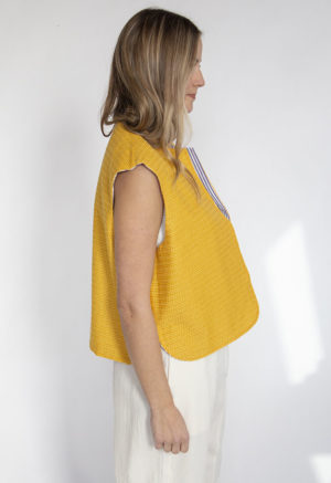 Side view of straight size model wearing Bright Marigold Reversible Vest.