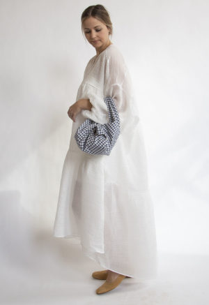 Side view of straight size model wearing White Limited-Run Double V Tiered Maxi Dress carrying Small Tie Tote.