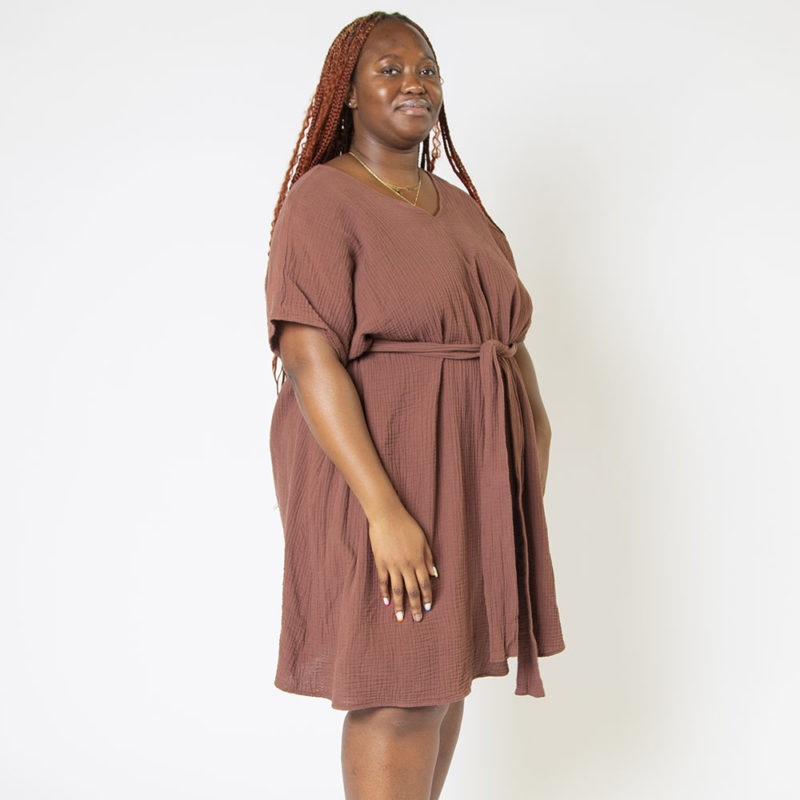 Front/side view of plus size model wearing Raisin Cotton Reversible Smock Dress.
