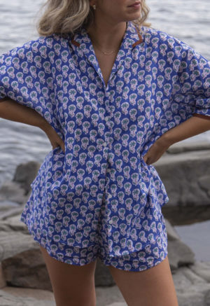 Close-up front view of straight size model wearing Dark Blue Floral Dolman Sleeve Button-Up and Dark Blue Floral Short Shorts.