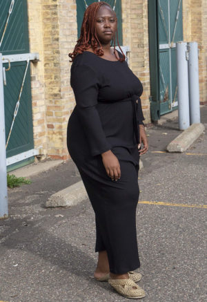 Front/side view of plus size model wearing Black Rib Long Sleeve Reversible Jumper.