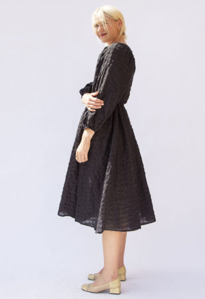 Side view of straight size model wearing Black Check Reversible Wrap Dress.