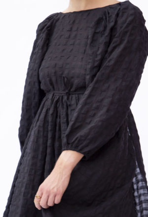 Close-up front view of straight size model wearing Black Check Reversible Wrap Dress.