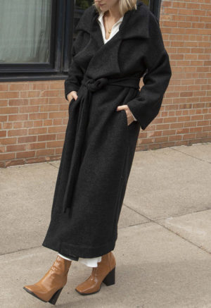 Front/side view of straight size model wearing Black Wool Oversized Lapel Coat.