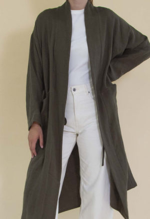 Women in dark green linen midi jacket worn over a white rib top and white jeans