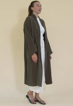 Women in dark green linen midi jacket worn over a white rib top and white jeans