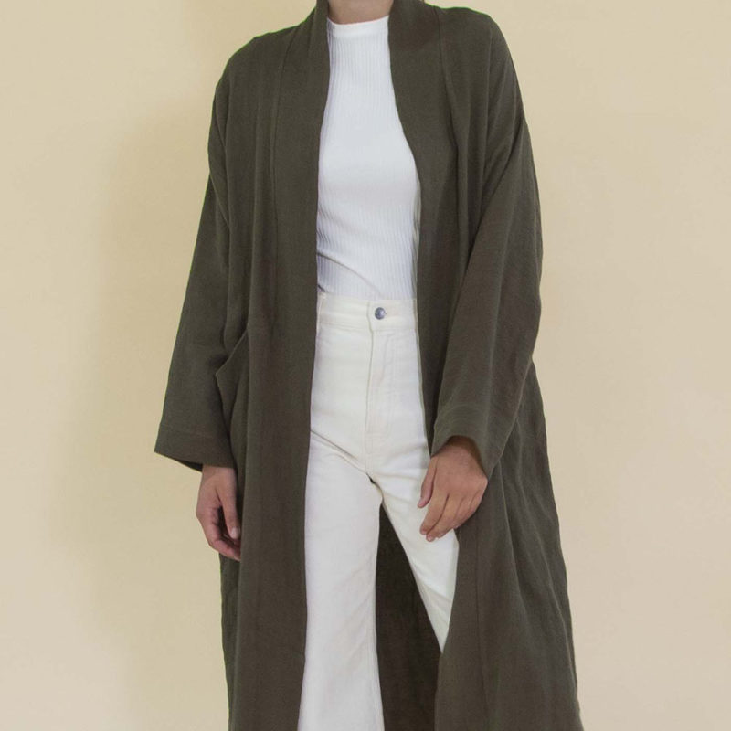 Women in dark green linen midi jacket worn over a white rib top and white jeans