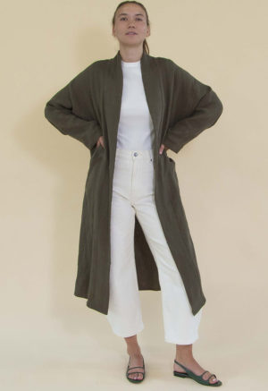 Women in dark green linen midi jacket worn over a white rib top and white jeans