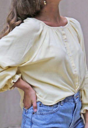 Front/side view of straight size model wearing Italian Straw Button-Up Ruffle Blouse.
