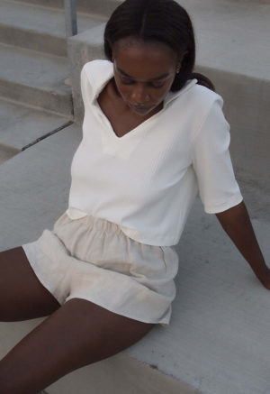 Front/side view of straight size model wearing Ivory Cropped Collar V-Neck Rib Top.