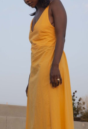 Side view of straight size model wearing Gold V-Neck Maxi Slip Dress.