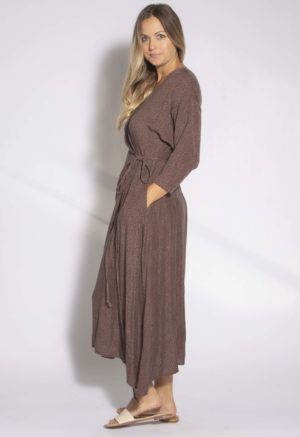 Side view of straight size model wearing Brown with Black Spots Wrap Dress.