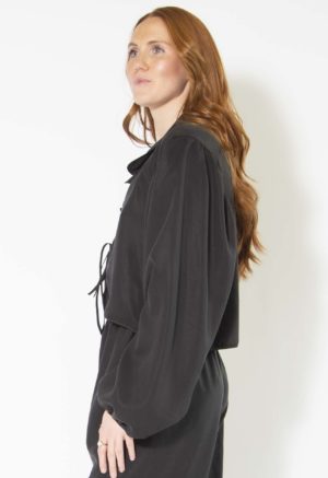 Side view of straight size model wearing Black Lyocell Tie Front Blouse and Cuff Pant.
