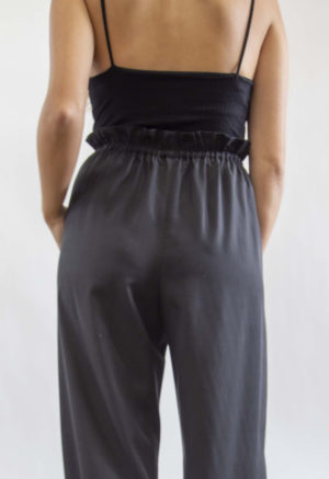 Back view of straight size model wearing Black Lyocell Paper Bag Trousers.