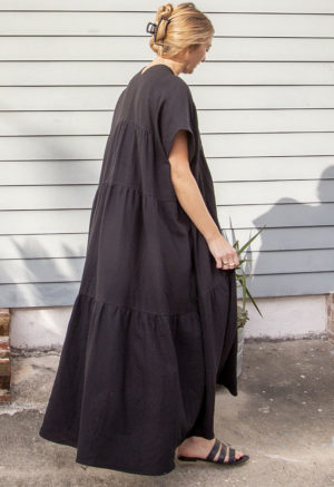 Side/back view of straight size model wearing Black Gauze Double V Tiered Maxi Dress.