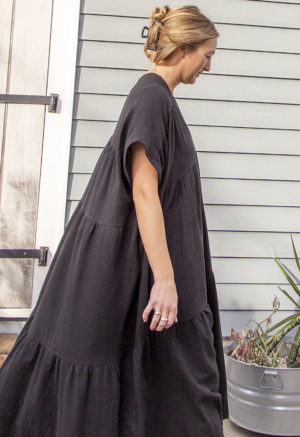Side view of straight size model wearing Black Gauze Double V Tiered Maxi Dress.