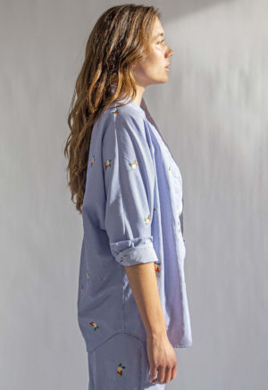 Side view of straight size model wearing Embroidered Blue Stripe Limited Run Long Sleeve Dolman Button-Up Top.
