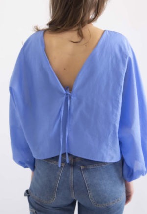 woman in cerulean blue balloon sleeve tie top and dark blue jeans