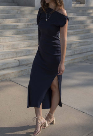 Woman in blue rib maxi length dress with an asymmetrical neck line and high slit on one side of the skirt