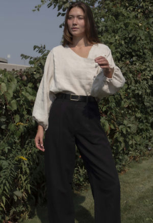 woman in oatmeal linen asymmetrical blouse with black slacks and black belt