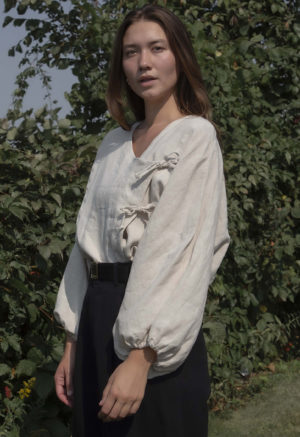 woman in oatmeal linen asymmetrical blouse with black slacks and black belt